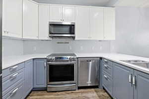 Kitchen with appliances with stainless steel finishes, white cabinets, and dark wood finished floors