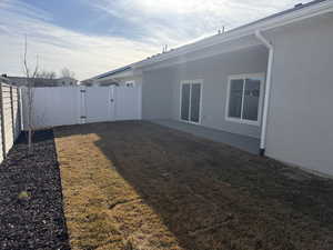 Fenced backyard featuring a gate and a patio