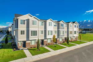 View of front of property with a residential view, brick siding, a mountain view, and a front lawn