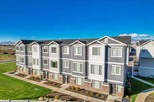 View of front of property featuring a front yard, brick siding, a residential view, and board and batten siding