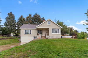 Bungalow-style house with a front lawn, a chimney, covered porch, and brick siding