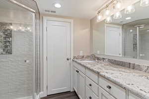 Bathroom featuring a stall shower, vanity, a textured ceiling, dark wood-type flooring, and recessed lighting