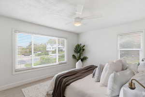 Carpeted bedroom with ceiling fan and a textured ceiling