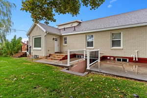 Back of property featuring roof with shingles, a yard, and brick siding