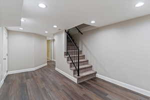 Below grade area with dark wood-style flooring, recessed lighting, and stairway