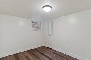 Unfurnished room featuring baseboards and dark wood finished floors