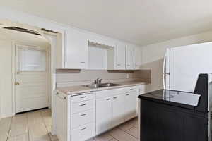 Kitchen featuring white cabinetry, light countertops, and freestanding refrigerator