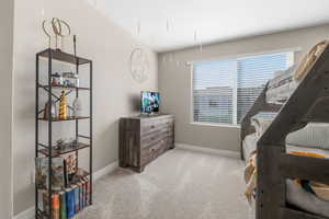 Bedroom featuring light carpet and baseboards
