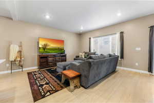 Living room with light wood finished floors and recessed lighting open great room feel