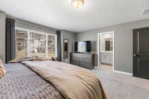 Bedroom featuring light carpet and a textured ceiling with ensuite bathroom