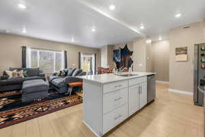 Kitchen with open floor plan, light wood-style flooring, appliances with stainless steel finishes, and recessed lighting