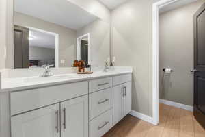 Bathroom with light wood-style flooring and double vanity with door to water closet