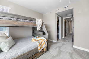 Bedroom with light carpet, a walk in closet, and a textured ceiling