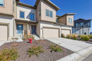View of front facade with concrete driveway, board and batten siding, a garage, driveway parking and a residential view