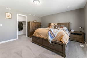 Bedroom featuring light colored carpet and a large walk in closet