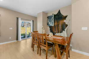 Dining area with baseboards and light wood-style floors open to family room and off of back patio