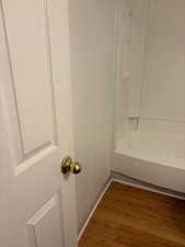 Detailed view of wood finished floors and shower / tub combination