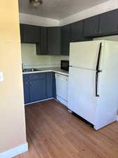 Kitchen with white appliances, light countertops, light wood-style floors, and a textured ceiling