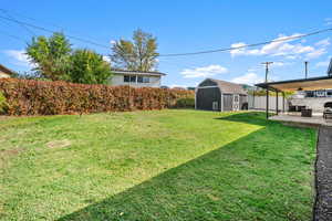 Fenced backyard with a storage unit and a patio area