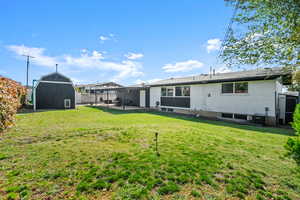 Back of property featuring a storage unit, a patio area, and a fenced backyard
