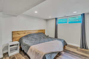 Bedroom with wood finished floors, a textured ceiling, and recessed lighting