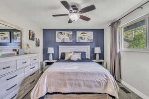 Carpeted bedroom featuring a textured ceiling and a ceiling fan