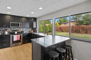 Kitchen with appliances with stainless steel finishes, recessed lighting, a breakfast bar area, a textured ceiling, and a peninsula