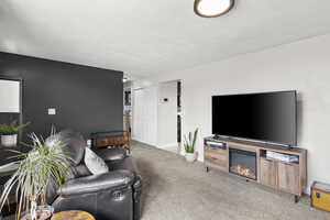 Living area featuring light carpet and a glass covered fireplace
