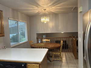 Dining area with light tile patterned floors and a chandelier