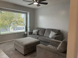 Living area with a ceiling fan, carpet flooring, and tile patterned floors