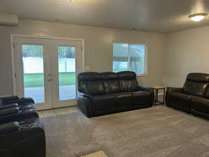 Living area with french doors, a textured ceiling, light carpet, and light tile patterned flooring