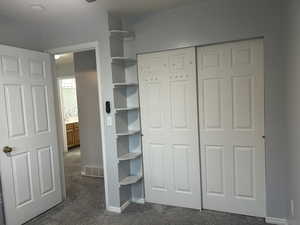 Unfurnished bedroom with dark colored carpet and a closet