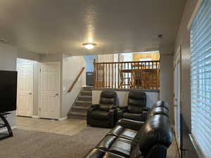 Home theater room featuring light tile patterned floors, a textured ceiling, and light colored carpet