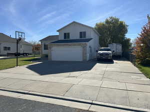 View of side of property with concrete driveway, brick siding, and an attached garage