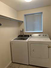 Laundry room with light tile patterned flooring and washing machine and clothes dryer