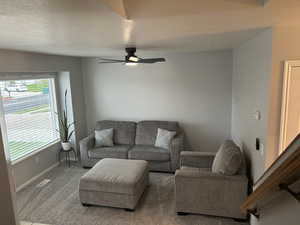 Carpeted living room featuring a textured ceiling and ceiling fan