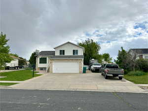 View of front facade featuring driveway, a garage, and roof with shingles