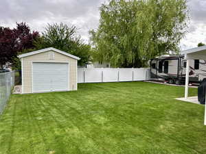 Fenced backyard featuring an outdoor structure and a detached garage