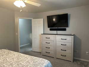 Bedroom featuring light carpet, a textured ceiling, and ceiling fan
