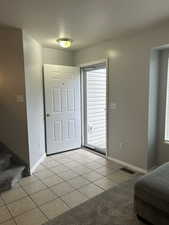 Entryway featuring light tile patterned floors, a textured ceiling, healthy amount of natural light, light carpet, and stairway