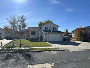 View of front of home featuring a front yard, driveway, a garage, and brick siding