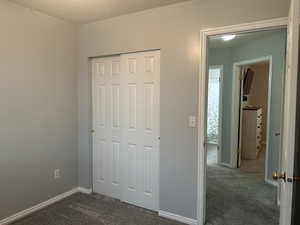 Unfurnished bedroom featuring dark colored carpet and a closet