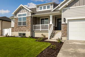 Entrance to property with stone siding, board and batten siding, a porch, and roof with shingles