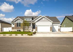 Craftsman-style house featuring board and batten siding, stone siding, driveway, and a garage