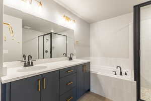 Full bath with a garden tub, double vanity, a stall shower, and light tile patterned floors