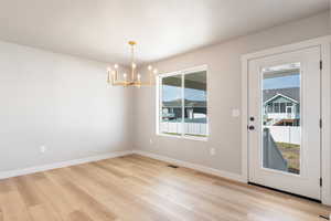 Unfurnished dining area with light wood finished floors and a chandelier
