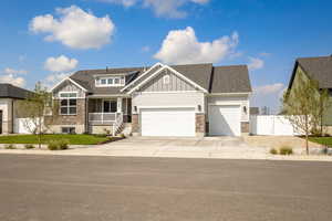 Craftsman inspired home featuring stone siding, board and batten siding, covered porch, roof with shingles, and concrete driveway