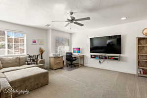 Loft with an office area, light colored carpet, ceiling fan, and a textured ceiling