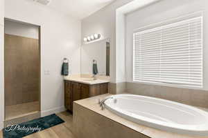 Bathroom featuring a garden tub, vanity, light wood-style floors, and walk in shower