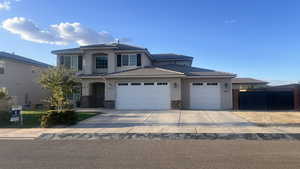 View of front of property with driveway, a garage, stone siding, and stucco siding
